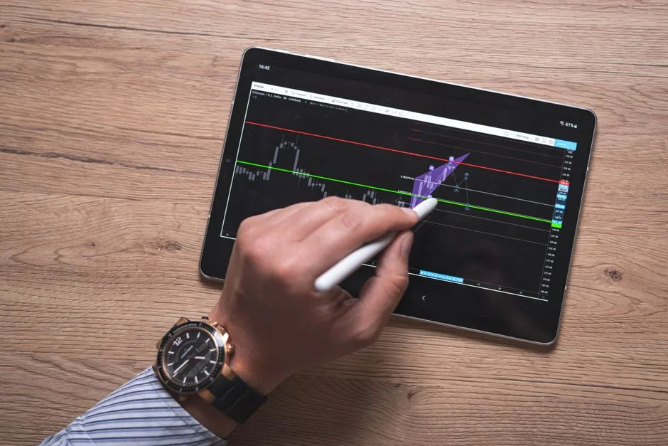 Une équipe examine des graphiques financiers et des données numériques sur des tablettes dans un environnement de bureau.